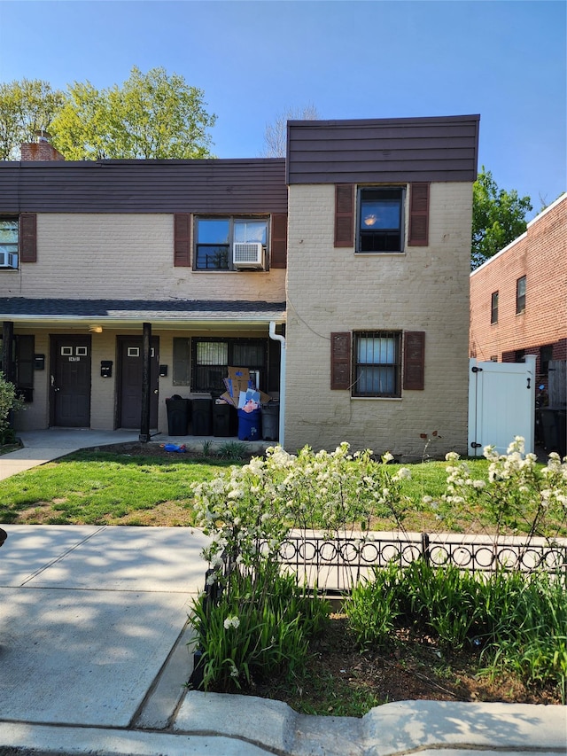 view of front facade with brick siding, cooling unit, a chimney, and fence