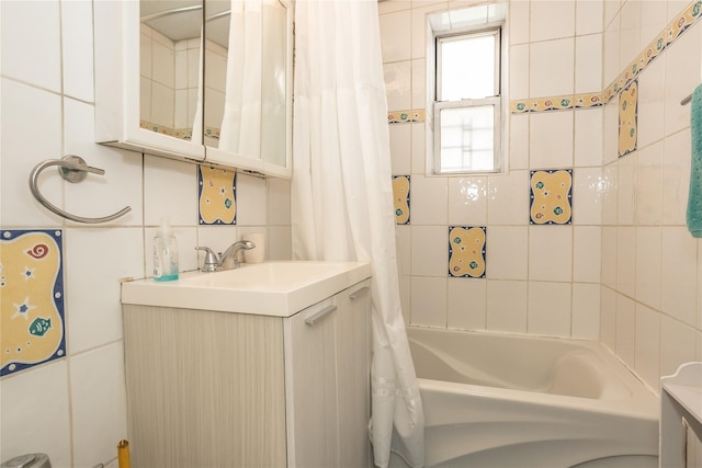 full bathroom featuring tile walls, shower / bath combo with shower curtain, and vanity