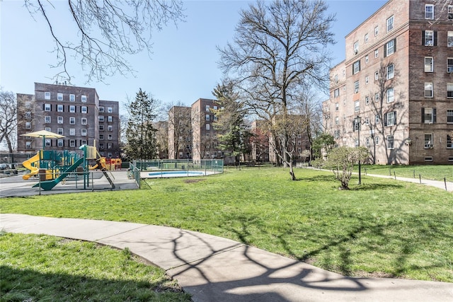 surrounding community with playground community, a yard, and fence