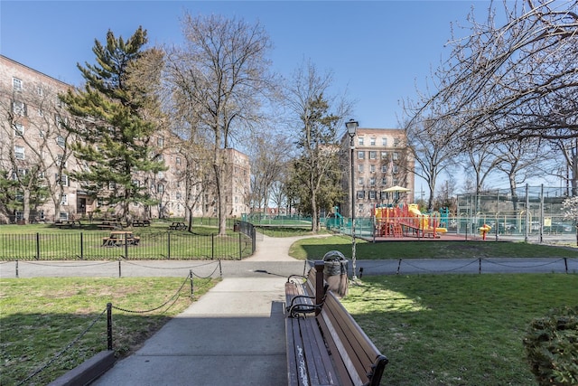 view of community with fence, playground community, and a lawn