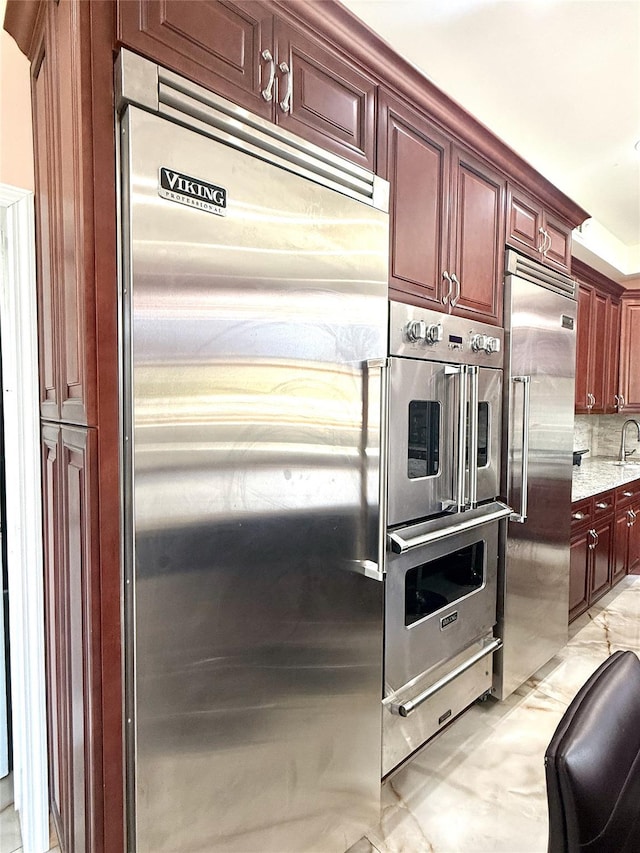 1601 Union Ave, Hewlett, NY 11557 - kitchen with dark brown cabinets, light stone counters, stainless steel appliances, and tasteful backsplash