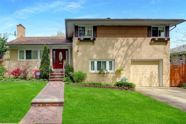 tri-level home with a garage, a chimney, a front lawn, concrete driveway, and brick siding