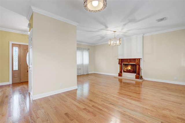 unfurnished living room with baseboards, visible vents, light wood finished floors, crown molding, and a notable chandelier