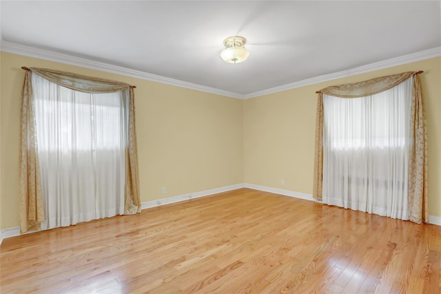 empty room with wood finished floors, baseboards, and ornamental molding