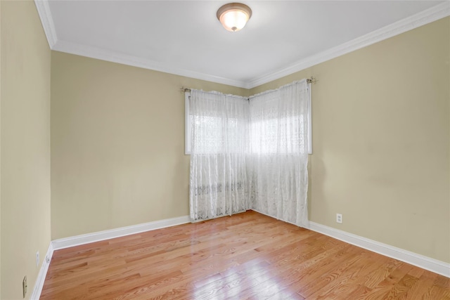 spare room with baseboards, crown molding, and wood finished floors