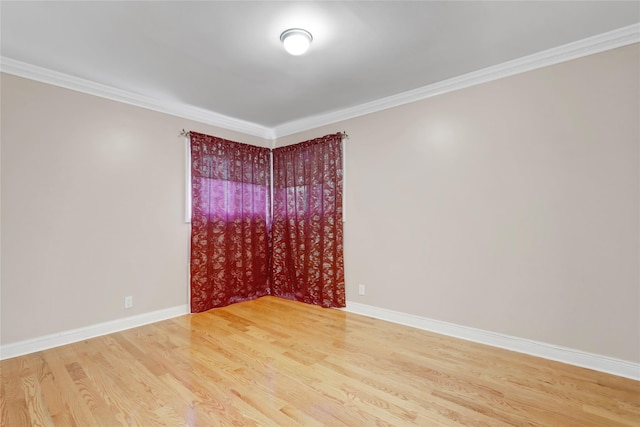 spare room featuring wood finished floors, baseboards, and ornamental molding