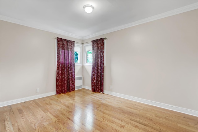 unfurnished room featuring light wood finished floors, ornamental molding, baseboards, and radiator heating unit