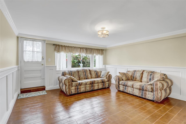 living room featuring wood finished floors, a decorative wall, wainscoting, and ornamental molding