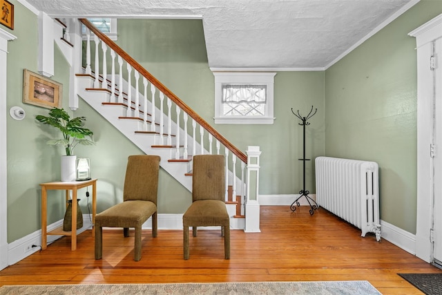 sitting room featuring baseboards, radiator heating unit, stairway, a textured ceiling, and hardwood / wood-style flooring