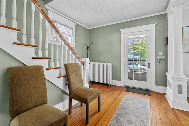 entryway with wood-type flooring, radiator, baseboards, ornate columns, and stairway