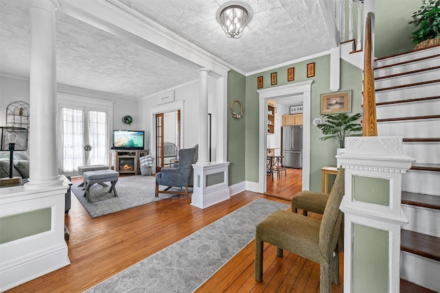 living area featuring ornate columns, crown molding, and hardwood / wood-style floors