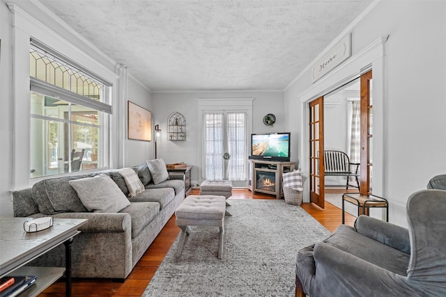 living room featuring french doors, a textured ceiling, ornamental molding, and wood finished floors