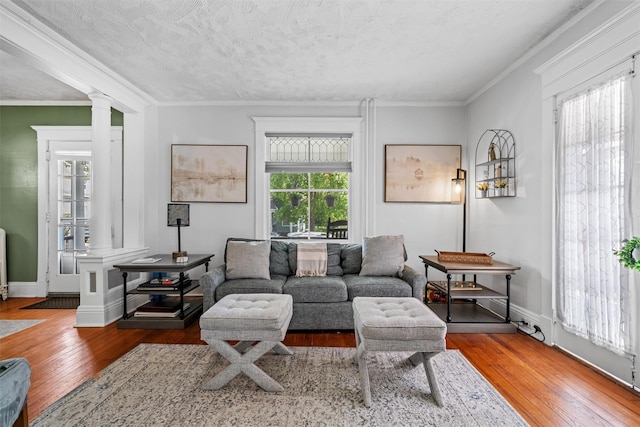 living area with crown molding, baseboards, ornate columns, and hardwood / wood-style floors