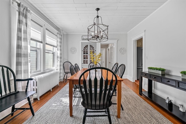 dining space featuring ornamental molding, radiator heating unit, a chandelier, and hardwood / wood-style floors