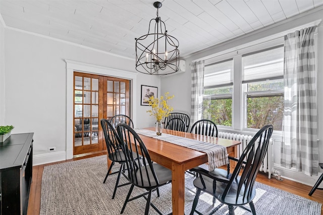 dining room featuring french doors, crown molding, wood finished floors, baseboards, and a notable chandelier