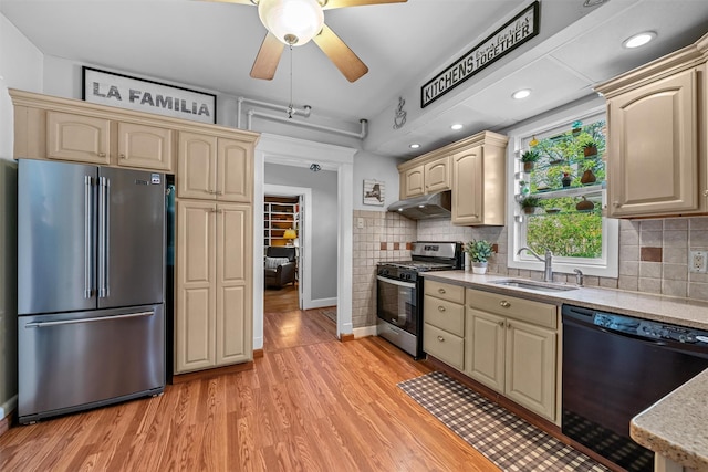 kitchen featuring a sink, appliances with stainless steel finishes, under cabinet range hood, and cream cabinetry