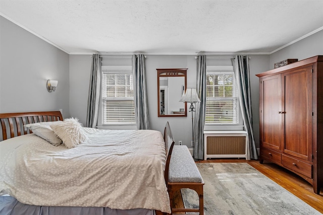 bedroom with crown molding, a textured ceiling, and wood finished floors