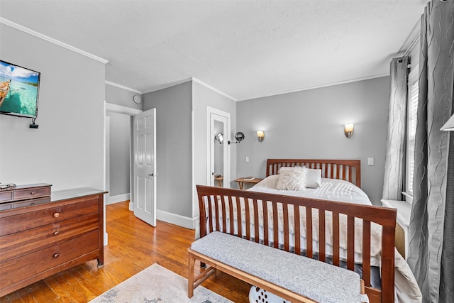bedroom featuring baseboards, ornamental molding, and light wood finished floors
