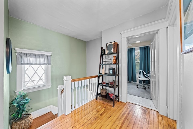 hallway with wood-type flooring, baseboards, and an upstairs landing