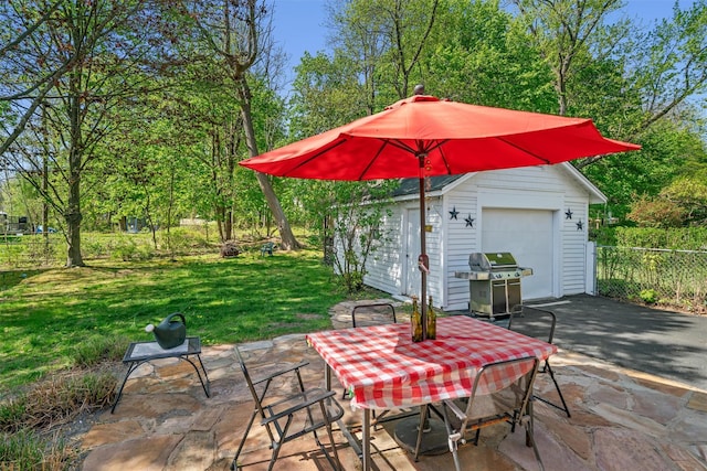view of patio featuring fence, outdoor dining space, a garage, area for grilling, and an outbuilding