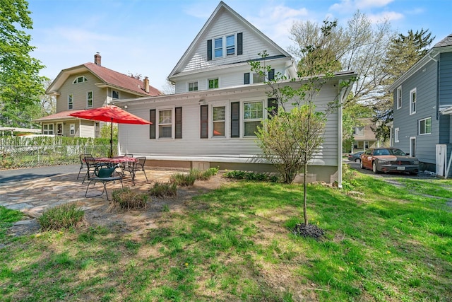 back of property featuring a lawn, fence, and a patio