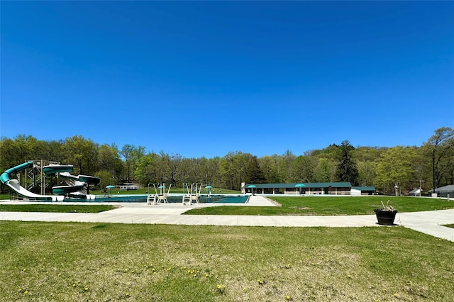 view of property's community featuring a lawn, a view of trees, and playground community