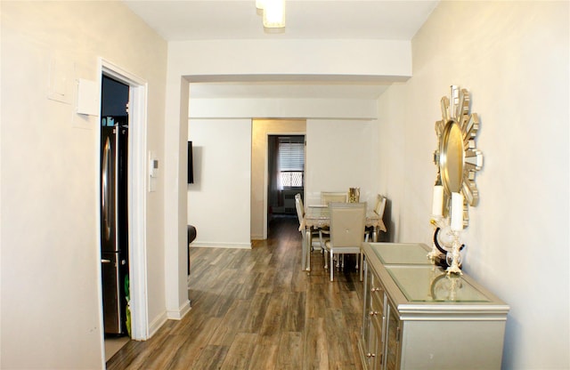corridor featuring baseboards and dark wood-style floors