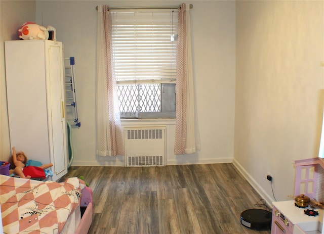 bedroom with radiator, baseboards, and wood finished floors