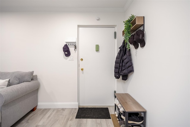 foyer entrance featuring wood finished floors, ornamental molding, and baseboards