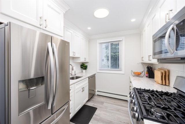 kitchen with appliances with stainless steel finishes, a baseboard heating unit, crown molding, white cabinets, and a sink
