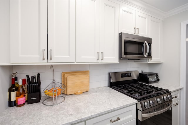 kitchen featuring appliances with stainless steel finishes, tasteful backsplash, white cabinetry, and ornamental molding