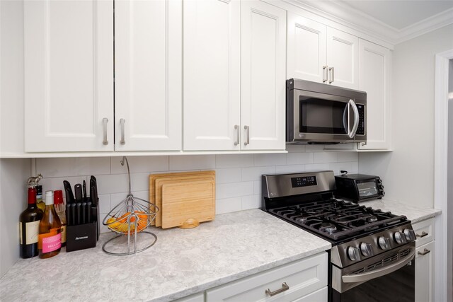 200 Merrick Rd Unit F, Amityville, NY 11701 - kitchen with stainless steel appliances, decorative backsplash, white cabinets, and ornamental molding
