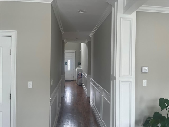 corridor featuring ornamental molding, dark wood finished floors, a decorative wall, and wainscoting