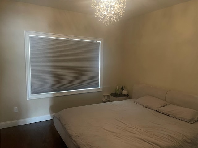 bedroom with baseboards, an inviting chandelier, and dark wood-style floors