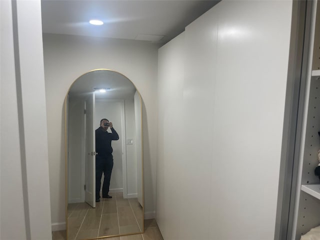 hallway featuring arched walkways and baseboards
