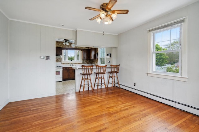 16 Edwards Ln E, Blue Point, NY 11715 - kitchen featuring white gas range, ceiling fan, a baseboard radiator, healthy amount of natural light, and ornamental molding