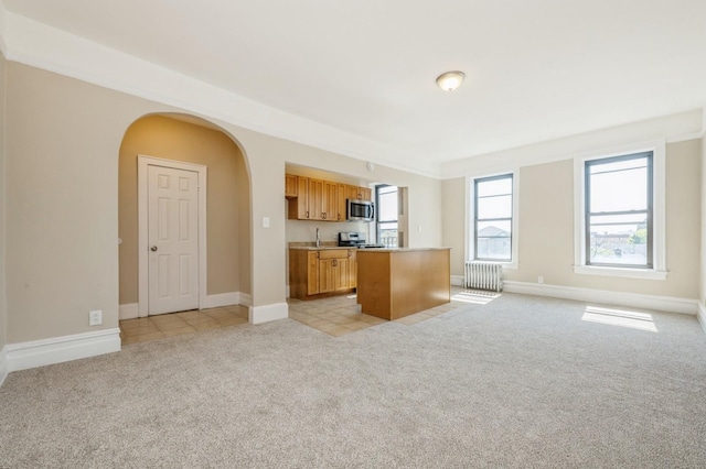 kitchen featuring a kitchen island, light carpet, open floor plan, light countertops, and stainless steel appliances