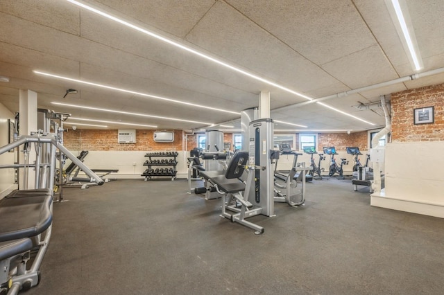 exercise room with brick wall and a wall mounted air conditioner