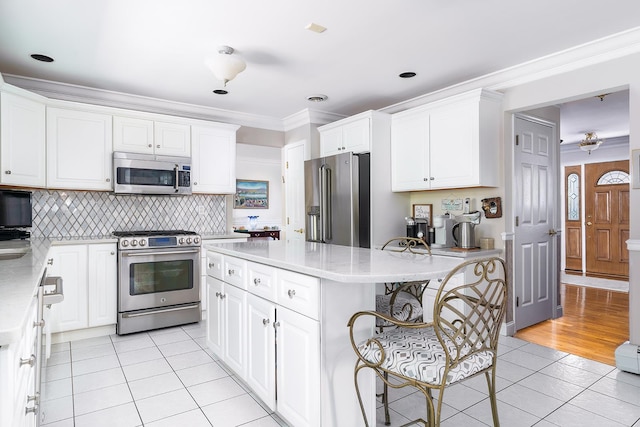 235 S Blvd, Nyack, NY 10960 - kitchen featuring appliances with stainless steel finishes, light tile patterned flooring, a kitchen bar, ornamental molding, and a center island