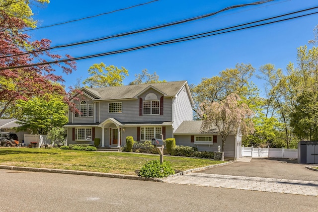 view of front facade featuring a front lawn, aphalt driveway, and fence