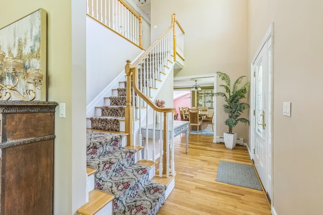 entryway featuring baseboards, stairs, wood finished floors, and a towering ceiling