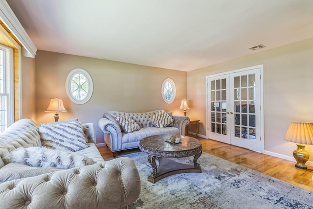 living area with visible vents, baseboards, wood finished floors, and french doors