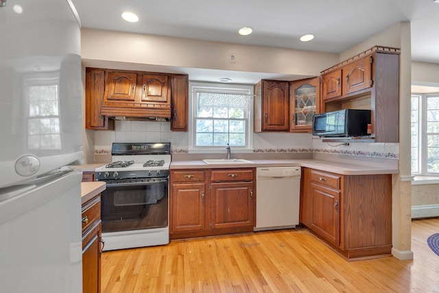 kitchen featuring a sink, brown cabinets, white appliances, and light countertops