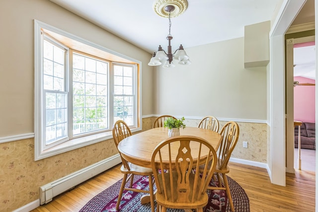 dining space featuring light wood-type flooring, a wainscoted wall, a baseboard radiator, a chandelier, and wallpapered walls