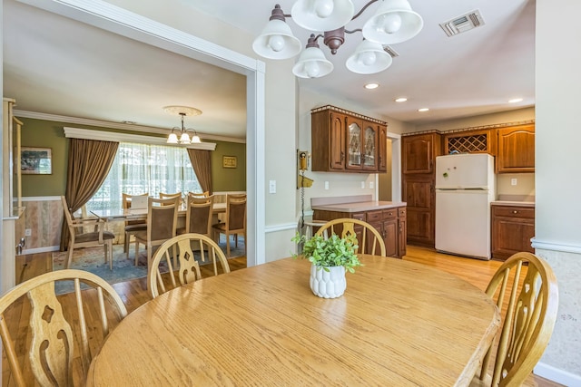 dining room with visible vents, crown molding, light wood-type flooring, an inviting chandelier, and recessed lighting