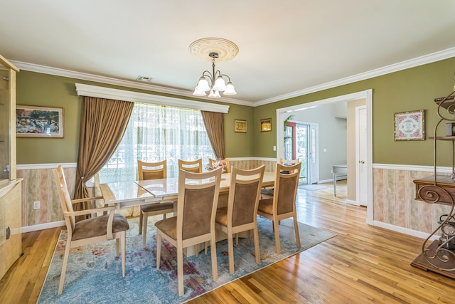 dining space with a chandelier, baseboards, light wood-type flooring, visible vents, and ornamental molding