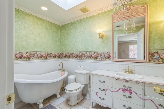bathroom featuring a freestanding bath, a skylight, wainscoting, and visible vents