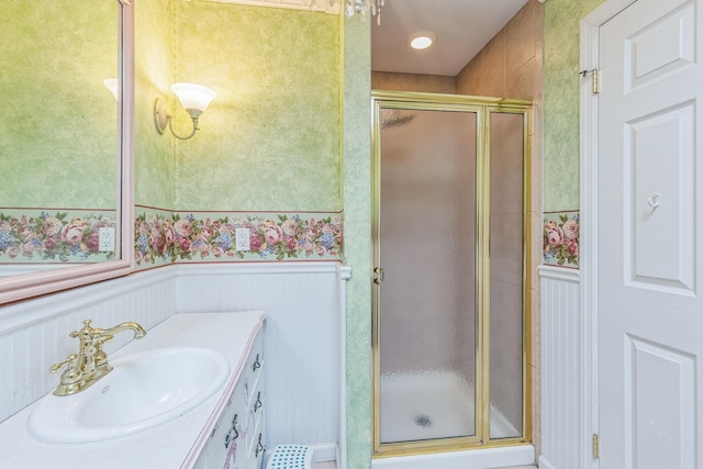 full bath with vanity, a wainscoted wall, a stall shower, and wallpapered walls