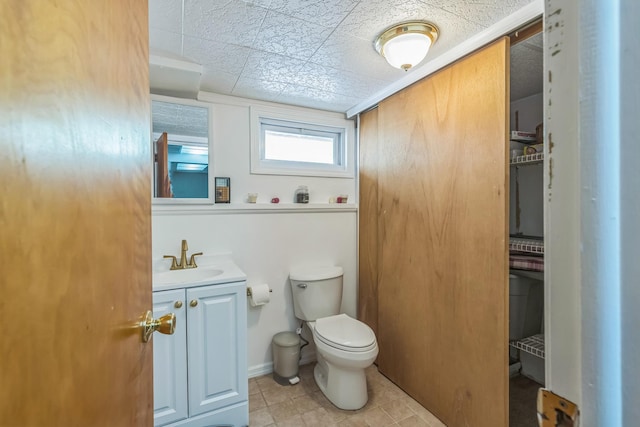 half bath featuring toilet, tile patterned flooring, and vanity