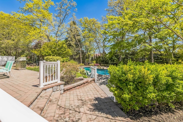 view of patio with an outdoor pool and a grill
